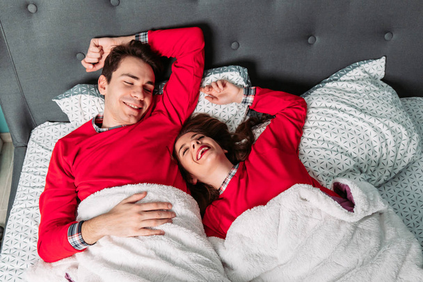 Couple lying in bed looking happy, smiling. Valentines day. Top view - Foto, imagen