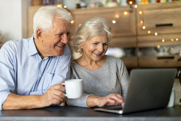 Seniorenpaar benutzt Laptop in der Küche - Foto, Bild