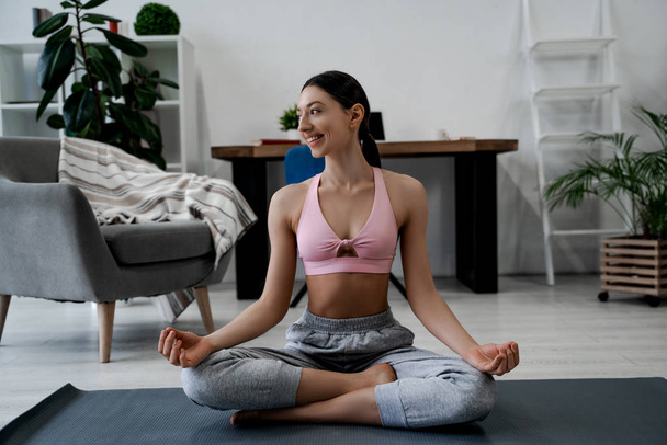 Jonge glimlachende aantrekkelijke sportieve vrouw die yoga beoefent, Ardha Padmasana oefeningen doet, mediteert in Half Lotus pose, sportkleding draagt. Gezonde mensen levensstijl, sterke vrouw lichaam - Foto, afbeelding
