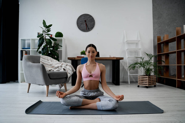 Beautiful sporty woman meditates indoor at home in her living room, keeps hands in yoga gesture, tries to relax after long hours of working, holds fingers in yoga sign. Healthy lifestyle people - Photo, Image