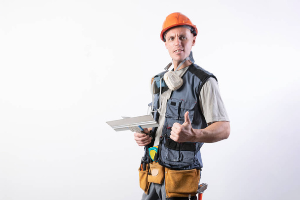 Builder with a spatula. And showing thumbs up. In work clothes and hard hat. On a light gray background. - Fotoğraf, Görsel