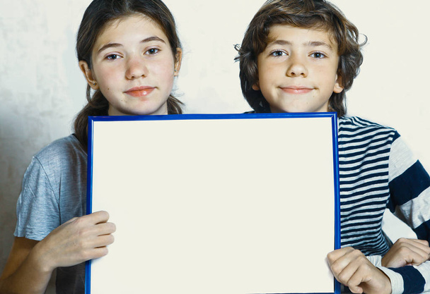 two kids boy and girl hold blank paper sheet in blue frame with  - Photo, Image