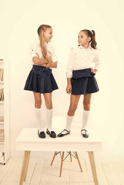 Preparing children for future. Happy little schoolgirls standing on table in classroom. Going together towards a brighter future. Educating future generation - 写真・画像