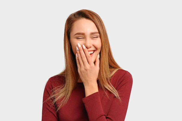 Girl laughs loudly covers mouth hand closes eyes - Foto, afbeelding