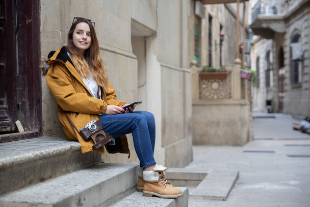 Foto eines jungen Touristenmädchens, das die Straßen von Baku erkundet. Stimmungsvolle Fotos von Teenager-Mädchen, die die Altstadt besuchen und Fotos von der Stadt machen. - Foto, Bild