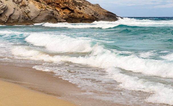 Costa arenosa con rocas y olas
 - Foto, imagen