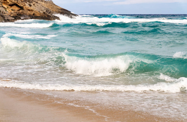 Homokos part sziklákkal és hullámokkal - Fotó, kép