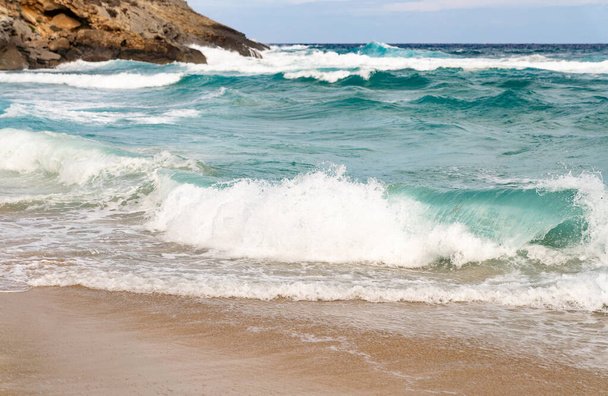 Costa arenosa con rocas y olas
 - Foto, imagen