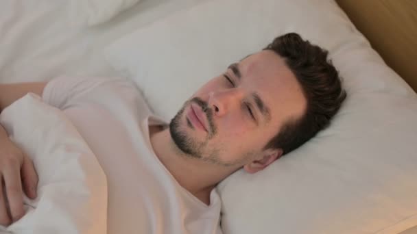 Portret van een jonge man met hoofdpijn in bed - Video