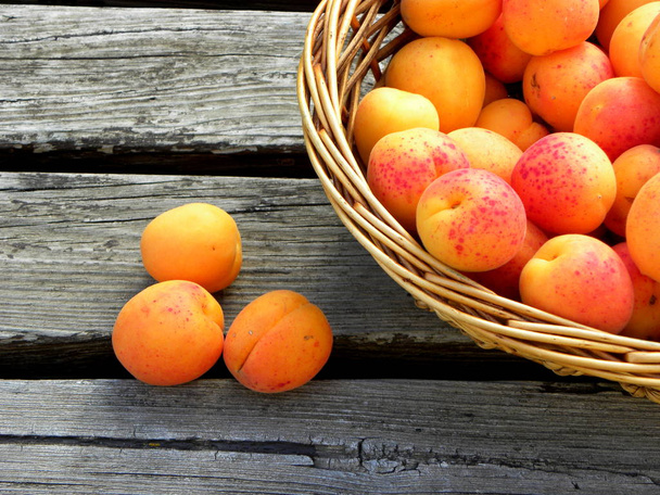 fresh apricots in a basket on wooden table. apricot pits - Foto, Imagen