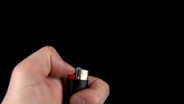 A man is trying to light a lighter. A man holds a lighter in his hand and spins a drum on a black background. Lighter produces sparks closeup. Slow motion. - Footage, Video