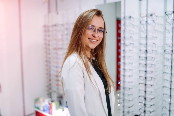Young beautiful girl in glasses near the stand in the optical store. Emotions. Ophthalmology. - Valokuva, kuva