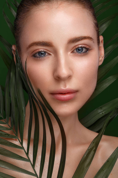 Beautiful fresh girl with perfect skin, natural make-up and green leaves. Beauty face. - Foto, afbeelding
