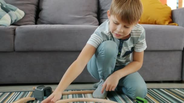 Happy child boy playing with wooden toy cars at home enjoying game in free time - Záběry, video