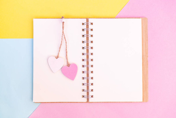 Open otebook with pink and white wooden hearts on them. Send message to your lover on Valentines day - Foto, Imagem