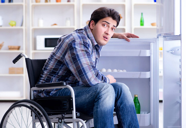 Jovem deficiente ferido homem abrindo a porta do frigorífico - Foto, Imagem