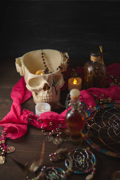 Scary still life with potions, skull, mortar, vintage bottles and candles on witch table. Halloween or esoteric concept. - Photo, Image