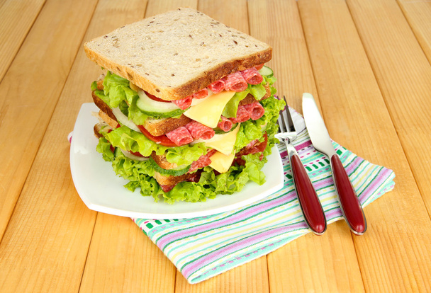 Huge sandwich on wooden table, on bright background - Valokuva, kuva