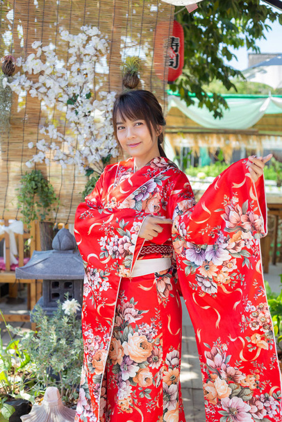Het meisje draagt een rode traditionele kimono, dat is de nationale jurk van Japan - Foto, afbeelding