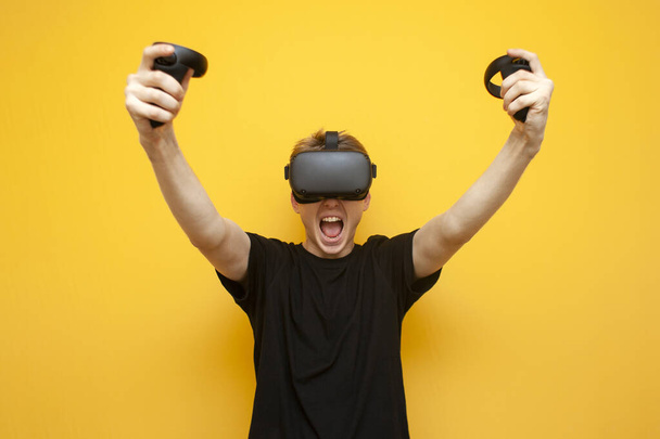 chico emocional con gafas VR gana un juego virtual, un jugador se regocija victoria sobre un fondo amarillo
 - Foto, imagen