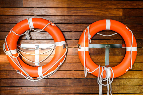Orangefarbener Rettungsring hängt mit Seil an einer Holzwand am Pool - Foto, Bild