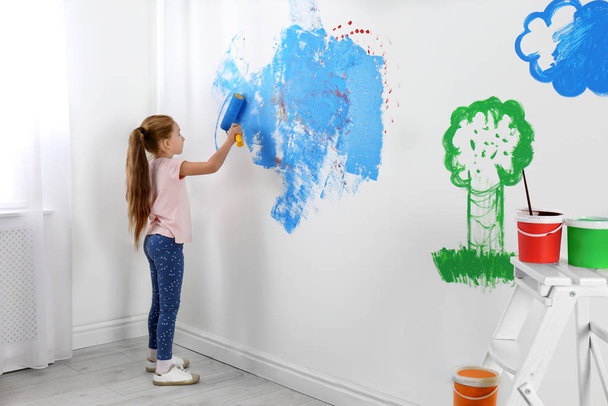 Little child painting wall with roller brush indoors - Foto, Bild