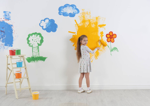 Little child painting wall with roller brush indoors - Foto, Imagem