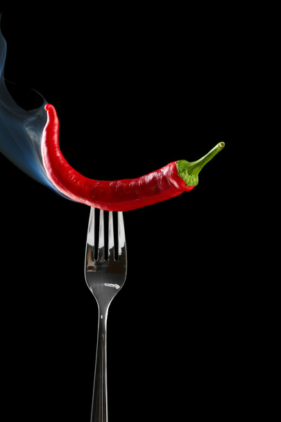 Red hot chili pepper on fork, isolated on black - Photo, Image