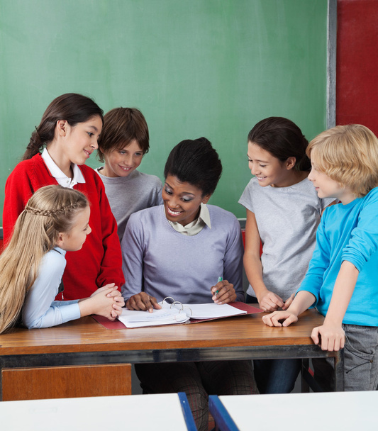 Female Professor Teaching Students At Desk - Фото, изображение