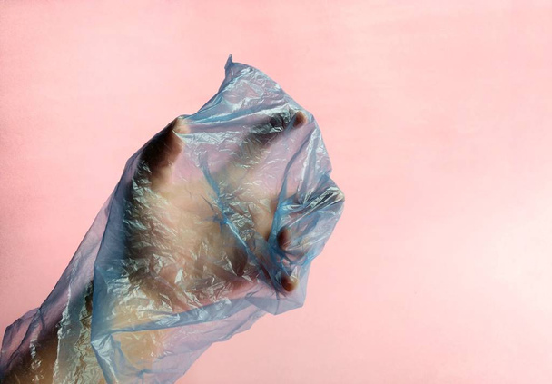 Hand with plastic bag on pink background. pollution concept - Фото, изображение