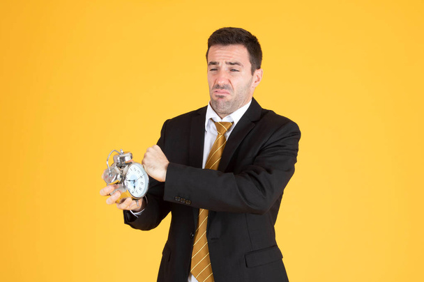 Retrato de un hombre de negocios guapo sosteniendo el reloj sintiéndose cansado o
 - Foto, imagen