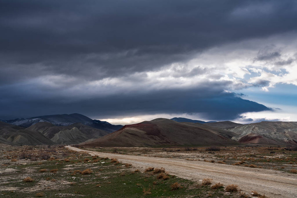 Dirt road to the mountains at stormy weather - Photo, image