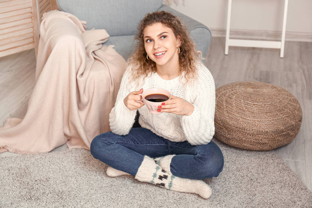 Piękna młoda kobieta w ciepłym swetrze pije herbatę w domu - Zdjęcie, obraz