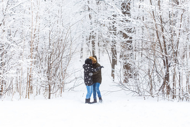 Mladý zamilovaný pár se baví v zasněženém lese. Aktivní zimní dovolená. - Fotografie, Obrázek