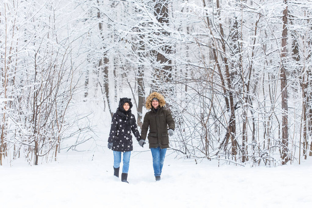 Fiatal szerelmesek sétálnak a havas erdőben. Aktív téli szünetek. - Fotó, kép