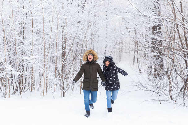 Happy couple walking through a snowy forest in winter - Foto, Imagen