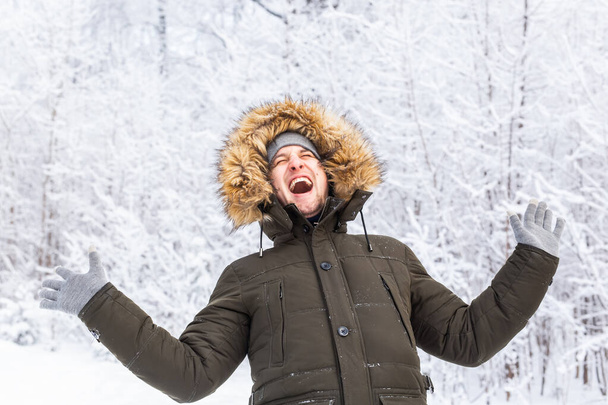 Knappe man in winterhoed grappig portret op besneeuwde natuur - Foto, afbeelding