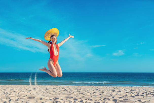 Женщина, наслаждающаяся пляжным отдыхом, прыгает высоко - Фото, изображение