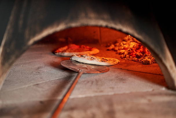 イタリア、ナポリのレストランで伝統的な木製のオーブンでおいしいマルゲリータピザを焼きました。オリジナルのナポリのピザ。赤熱石炭. - 写真・画像