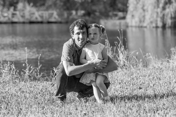 Családi portré. Egy apa megöleli a lányát. A háttérben a tó. - Fotó, kép