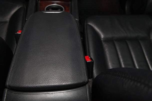 Close-up on the car front armrest with black leather trim, butto - Photo, Image