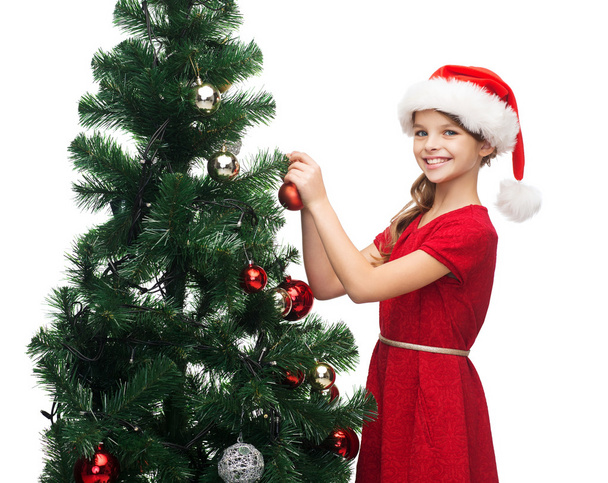 Smiling girl in santa helper hat decorating a tree - Valokuva, kuva