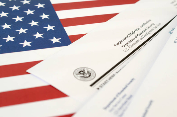 I-9 İş Bulma Yetkinliği Onaylama Formu, Birleşik Devletler bayrağında İç Güvenlik Bakanlığı 'ndan gelen zarfla birlikte duruyor. - Fotoğraf, Görsel