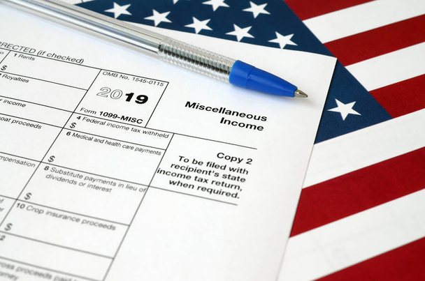 Formulaire 1099-misc Revenus divers et stylo bleu sur drapeau des États-Unis. Formulaire fiscal des services fiscaux internes
 - Photo, image