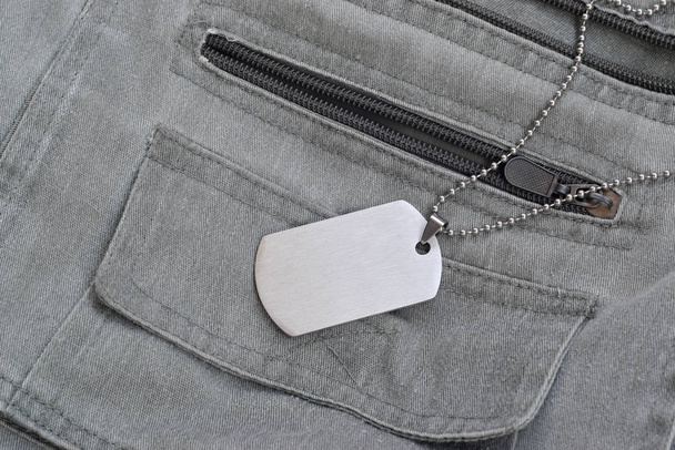 Perles militaires argentées avec étiquette pour chien sur gilet gris foncé avec poches
 - Photo, image