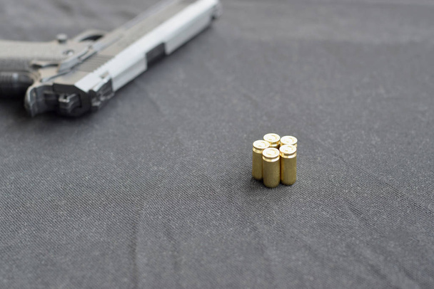 9mm Kugeln und Pistole liegen auf einem schwarzen Stoff. ein Set an Schießständen oder ein Selbstverteidigungsset - Foto, Bild
