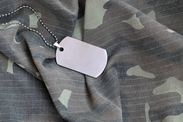 Perles militaires argentées avec étiquette de chien sur uniforme de fatigue camouflage
 - Photo, image