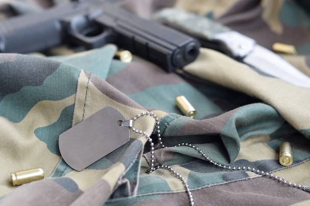 Exército Dog tag token com balas de 9mm e pistola mentira em tecido verde camuflagem dobrada
 - Foto, Imagem