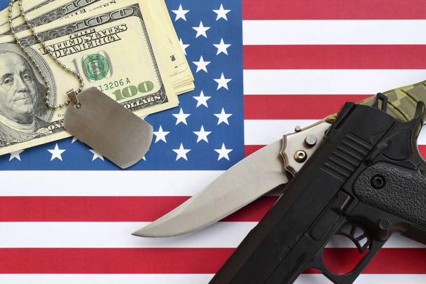 Zblízka dolarové peníze se zbraněmi a vojenskými odznaky na vlajce Spojených států. Vojenské síly, financování a koncepce národních služeb - Fotografie, Obrázek