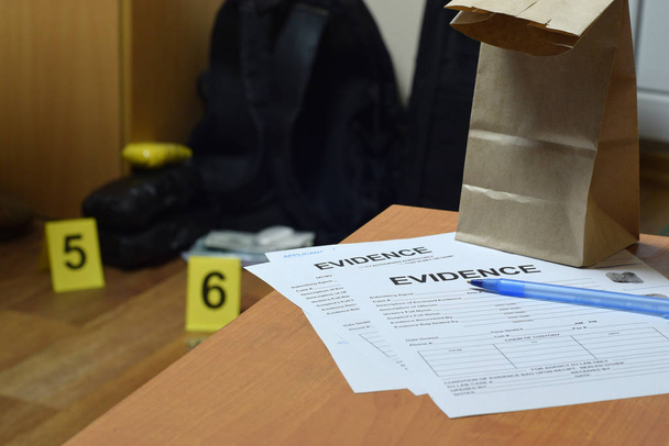 Beweismittelkette aus Verwahrungsetiketten und brauner Papiertüte liegt mit großen Heroinpäckchen und Päckchen voller Geldscheine als Beweismittel im Tatortermittlungsprozess vor dem Hintergrund - Foto, Bild